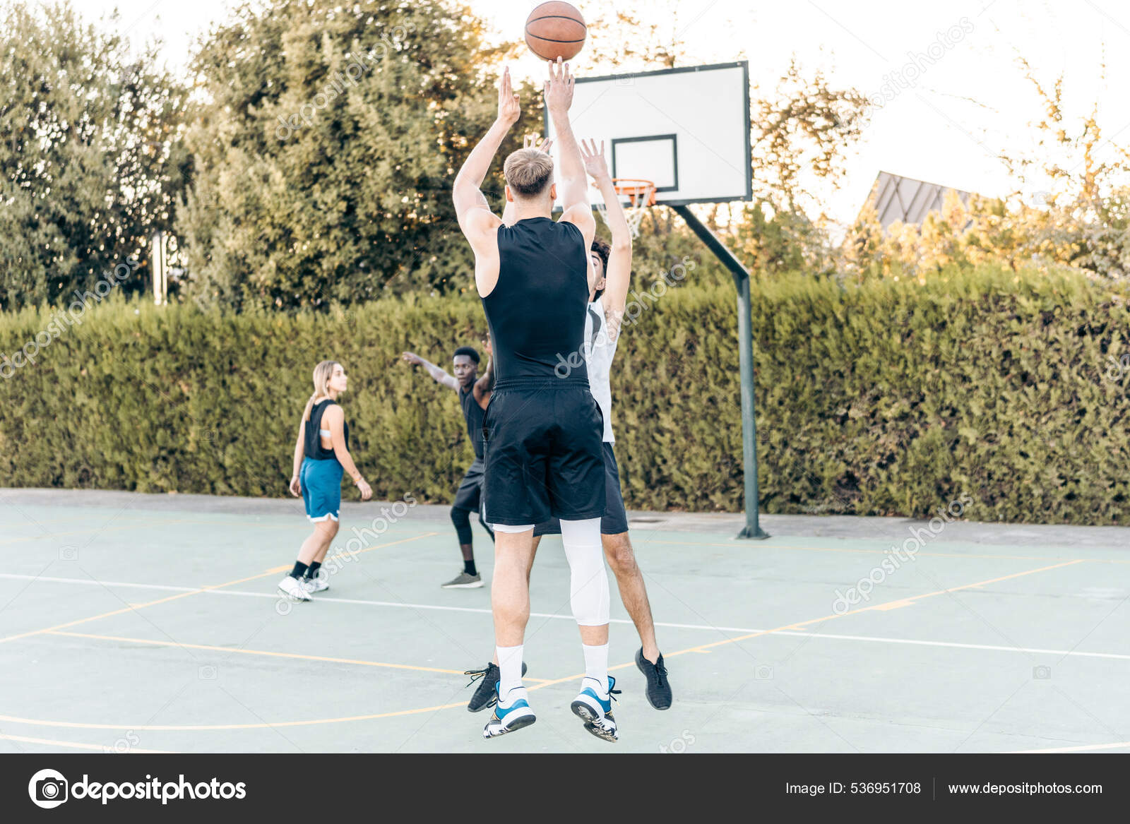 Grupo de amigos jogando basquete em uma quadra pública ao ar livre