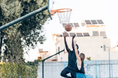 Arkadaşlar arasındaki bir maç sırasında basket atmak için zıplayan bir adam.