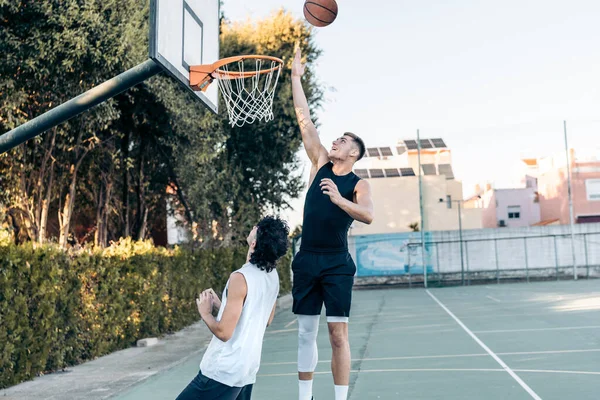 Uomo alto che fa un tappo giocare a basket in un campo all'aperto — Foto Stock