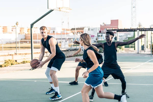 Uomo che difende una palla mentre gioca a basket con gli amici in un campo all'aperto — Foto Stock