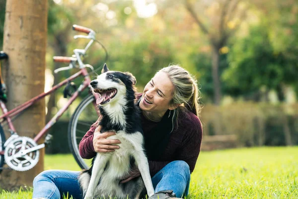 Kvinna klappa en hund sitter på en park — Stockfoto