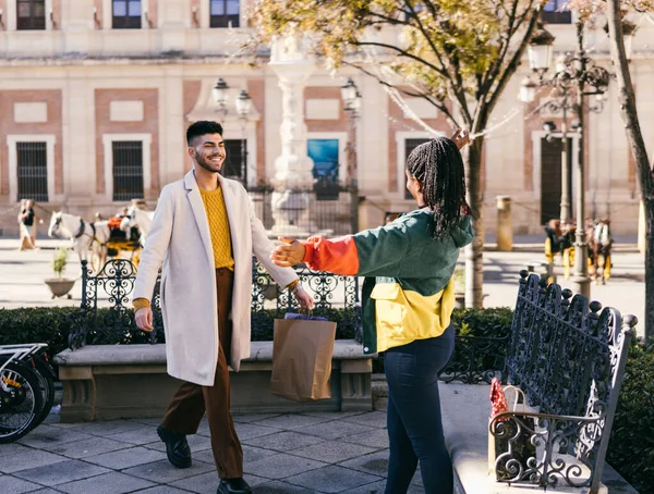 African woman opening her arms to embrace a man arriving with a present outdoors — стокове фото