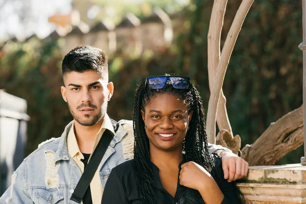 Two friends of different ethnicities standing smiling to the camera in a park — Stock Photo, Image