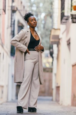 Afro woman posing while looking at the camera with a cocky expression outdoors