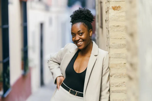 Afro woman with her hand on her waist smiling while looking at the camera
