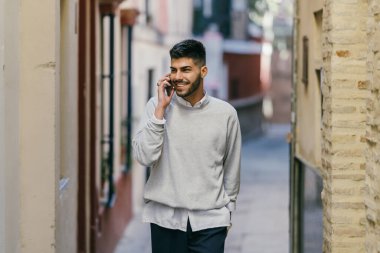 Young caucasian man in modern clothes talking to the mobile outdoors