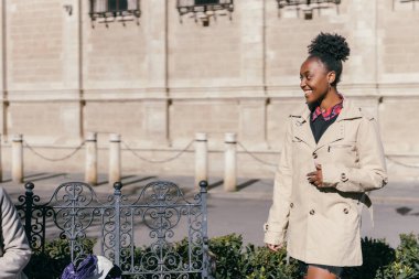 African woman standing in a park with a freshly given coat