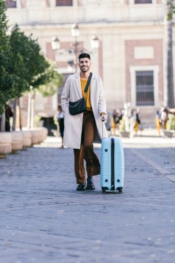 Man with coat carrying a suitcase on the street