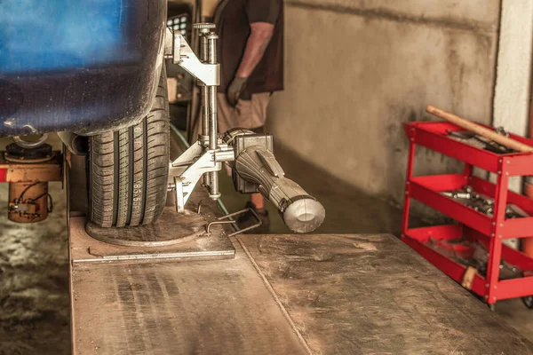 Mecánico junto a un coche levantado en un garaje donde se repara en un garaje — Foto de Stock