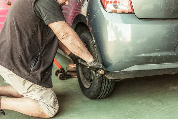 Mechanic fitting the wheel on a car in a workshop — Foto de Stock