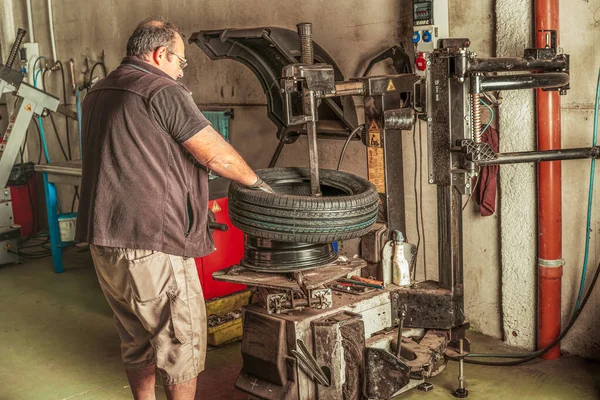 Mecánico que utiliza maquinaria eléctrica para reparar y equilibrar un neumático de automóvil — Foto de Stock