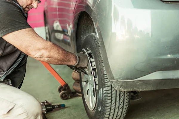 Mecánica de eliminación de tapacubos de un coche para reparar el neumático — Foto de Stock