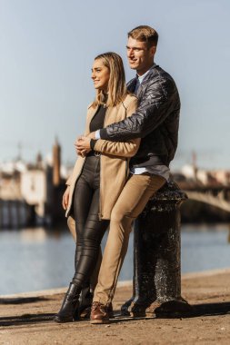 Bir çift liman kordonuna sarılıyor ve yaslanıyor.