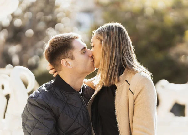Ung kvinna kysser sin pojkvän när hon sitter i hans knä — Stockfoto