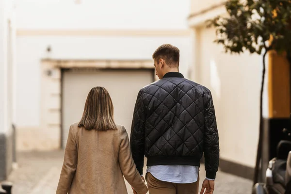 Vista posteriore di una sposa e uno sposo che passeggiano per le strade di una città. — Foto Stock