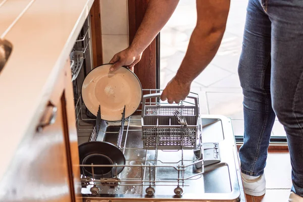 一个把脏盘子放进洗碗机的人 — 图库照片