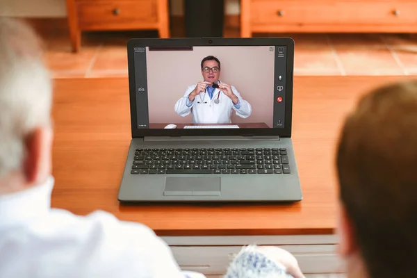 Un médico explica cómo utilizar un oxímetro a dos personas mayores por videoconferencia — Foto de Stock