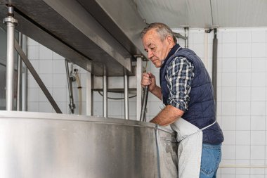 Yaşlı adam metal konteynırdaki son kaymağı topluyor.