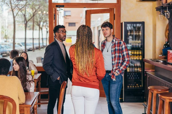 3 personas de diferentes etnias conversando dentro de un bar — Foto de Stock