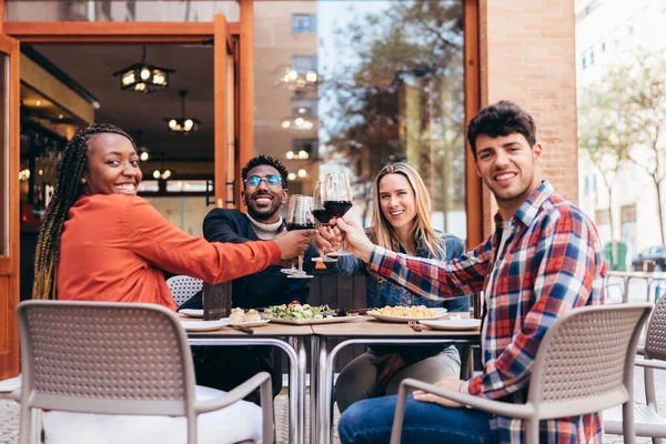 四个笑容满面的不同种族朋友的画像，用红酒祝酒 — 图库照片
