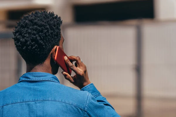 Genç Afro adam cep telefonuyla konuşuyor. Arkadan görüldüğü gibi.