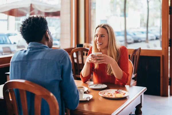 Pareja multiétnica conversar mientras se sienta en una mesa de bar y beber café — Foto de Stock