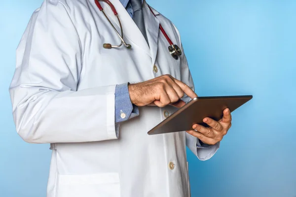 Beyaz önlüklü, tabletle çalışan tanınmayan bir doktor.