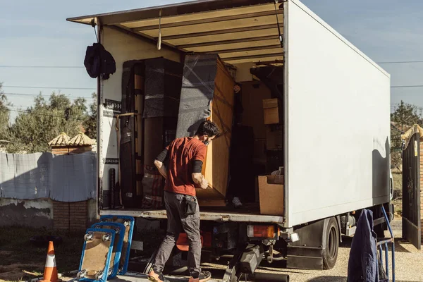 two men loading a piece of furniture wrapped in blankets onto a moving truck