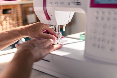 Close-up of a detail of a womans hands sewing with a sewing machine