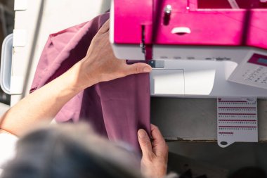 Dikiş makinesinde kumaşla çalışan terzi ellerinin havadan görünüşü