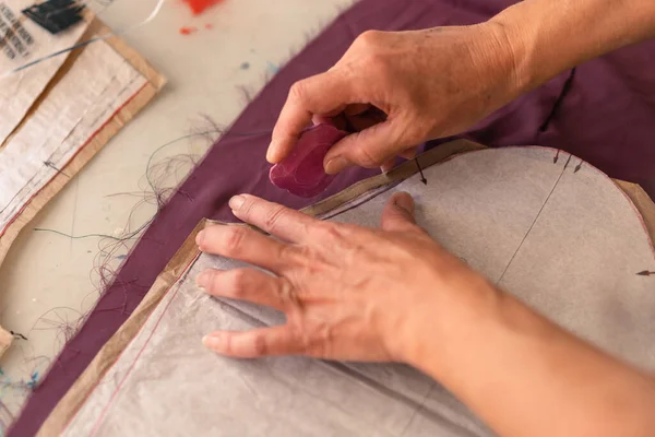 Close-up of the seamstress hands outlining garment pattern with chalk