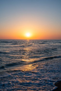 Denizde gün batımının dikey fotoğrafının tam görüntüsü.