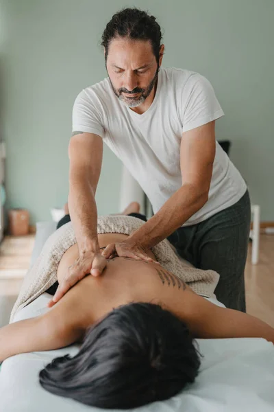 vertical photo of a masseur giving a massage to a patient lying on a massage table. Massage