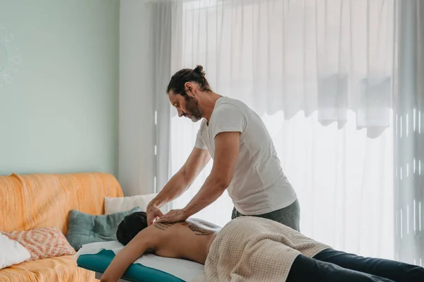 therapist standing massaging a tattooed womans neck. Massage