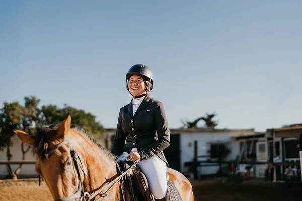 a smiling rider mounted on horseback in equestrian uniform. Horseback riding school