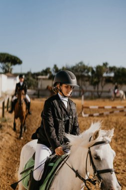 12-year-old girl jogging white pony at riding school. Horseback riding