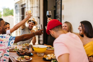 Bir grup arkadaş barbekü yerken kadeh kaldırıyor. Kutlama