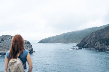 San Juan de Gaztelugatxe 'nin tepesinden sahili izleyen bir kadın. Seyahat