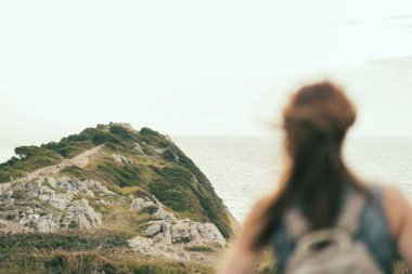 Uçurumun tepesindeki kadın ufka bakıyor. Sinek.
