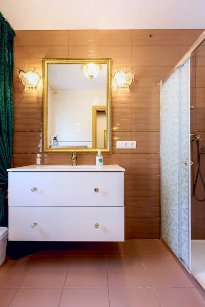 Mirror in a light frame with furniture in a bathroom.