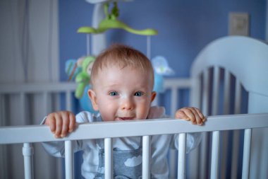 Sevimli bebek beşiğinde yatar ve gülümser..