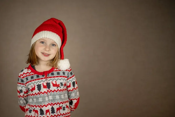 Menina em chapéu de santa e pijama de Ano Novo em um fundo sólido — Fotografia de Stock