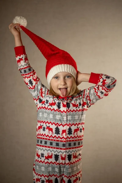 穿着桑塔帽和新年睡衣、背景坚实的女孩 — 图库照片