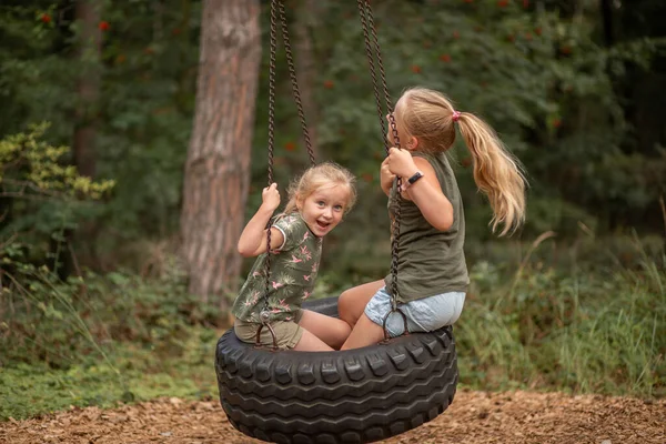 two funny girls swing on a swing