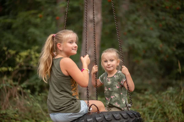 two funny girls swing on a swing