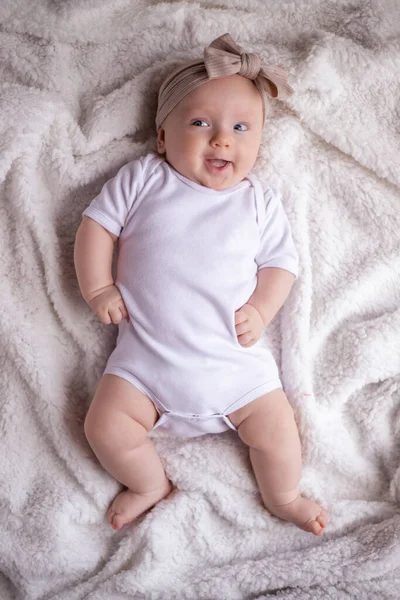小女孩躺在白色的毛毯上 身穿白色衣服 面带微笑 看着相机 婴儿的早晨 婴儿的概念 — 图库照片