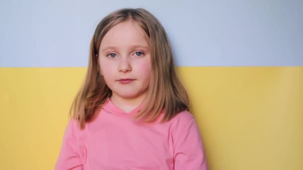 女の子はウクライナの国旗を背景に手で心を見せ — ストック動画