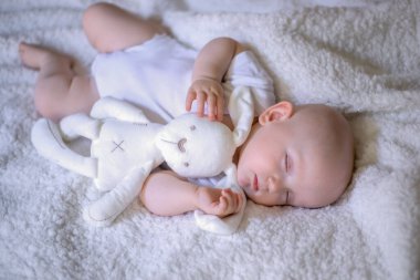 Yatakta uyuyan bebek, elinde oyuncak ayıyla. seçici odak