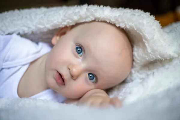 笑着看着相机的宝宝在白色的毯子下 选择性重点 — 图库照片