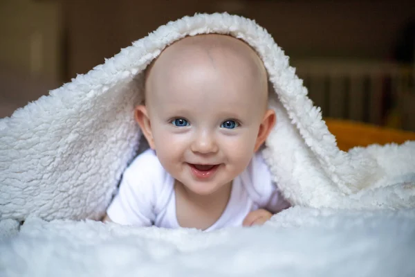 笑着看着相机的宝宝在白色的毯子下 选择性重点 — 图库照片